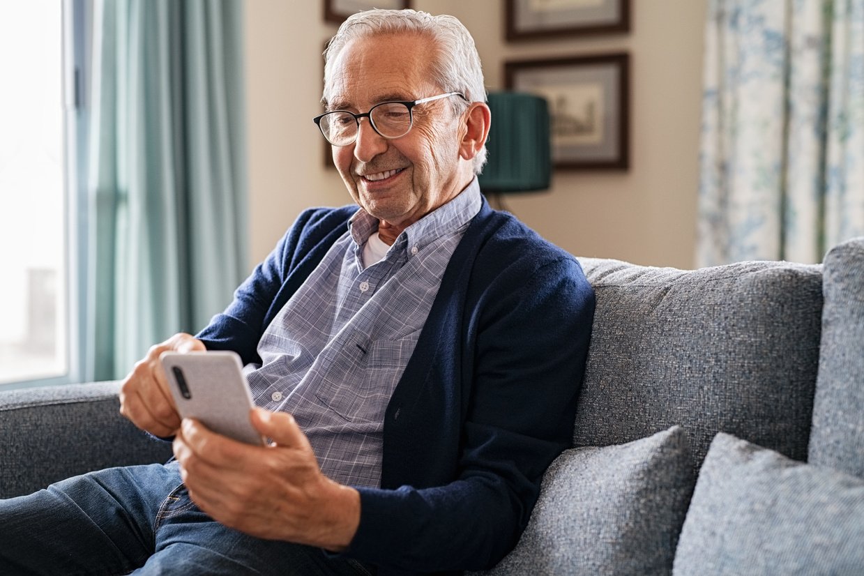 Happy Senior Man Using Phone at Home